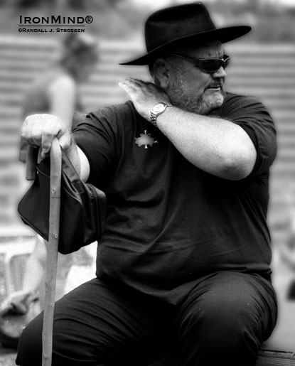 “Get me a cold one and be fast about it!” seems like the perfect caption as Douglas Edmunds referees at Odd Haugen’s 2001 Beauty and the Beast strongman contest.  IronMind® | Randall J. Strossen photo.