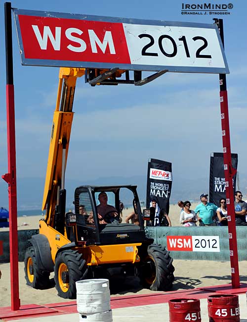 Yesterday, the qualifying heats began with the Keg Toss, an event that tests explosive power modulated by the need to maintain accuracy and also carrying the requirement of having sufficient stamina to make the full run before running out of gas.  Misha Koklyaev (Russia) was expected to deliver a stunning performance and he did: Koklyaev hit the World’s Strongest Man sign so hard with a barrel that he knocked it off its perch, but some intensive beach-based blacksmithing followed by all-purpose Jimmy Pollock threading the needle had the sign rehung and the show was back on the road in short order.  Pollock received a standing ovation when he greased the landing.  IronMind® | Randall J. Strossen photo.