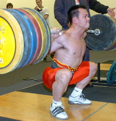 69-kg Zhang Guozheng (China) squats a routine 210 kg, as he and teammate Shi Zhiyong loosened up at Performance One yesterday afternoon. IronMind® | Randall J. Strossen, Ph.D photo.